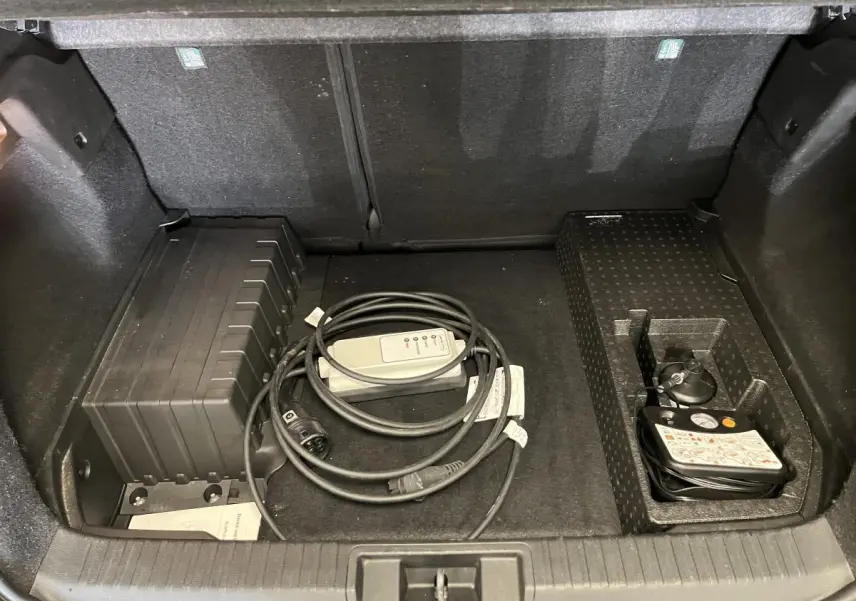 Coffre ouvert d'un Renault Captur hybride rechargeable 2022, montrant le rangement avec câble de recharge et kit de gonflage.