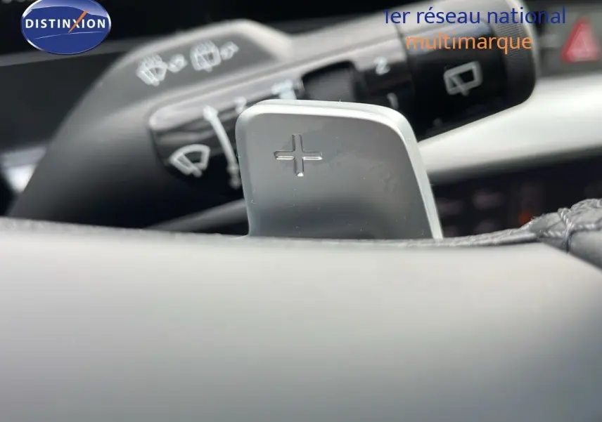 Gros plan sur la palette de changement de vitesse "+" du volant du KIA Sportage gris foncé 2025, intérieur moderne.