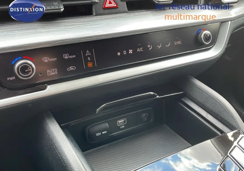 Détail de la console centrale du Kia Sportage 2025 gris foncé, montrant commandes climatisation et ports USB/12V.