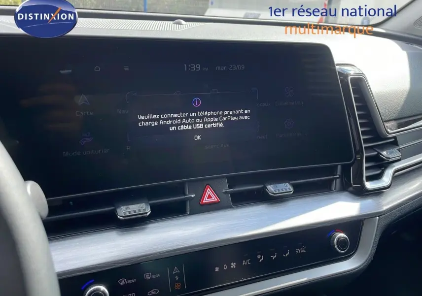 Tableau de bord intérieur du Kia Sportage 2025, écran tactile central et commandes climatisation visibles, finition moderne noire.