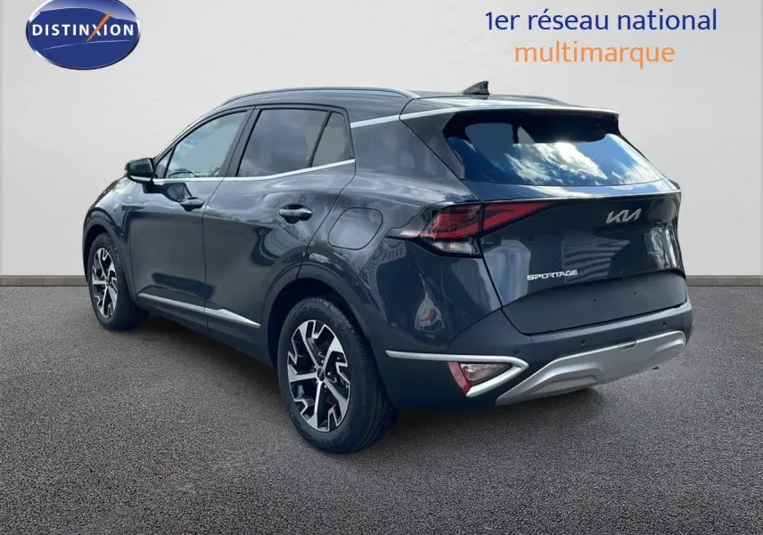 KIA Sportage gris foncé métal vu en 3/4 arrière côté gauche, avec jantes alliage et feux LED distinctifs.