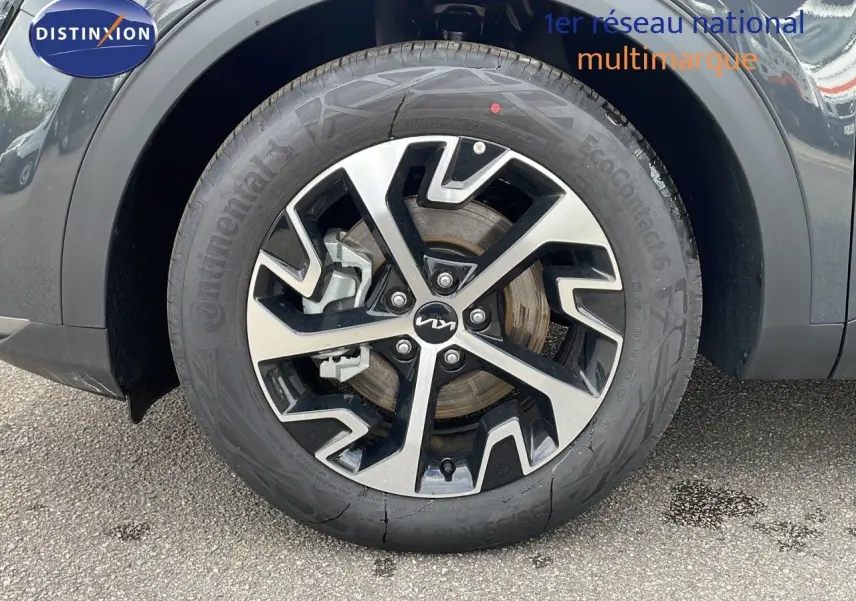 Gros plan sur la roue avant gauche du KIA SPORTAGE gris foncé métal avec jante alliage bicolore au design moderne.