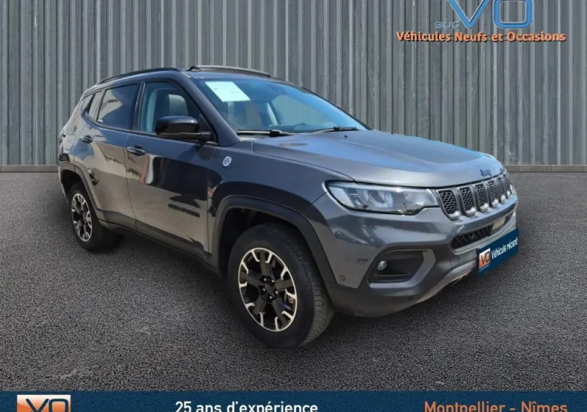 Jeep Compass Trailhawk gris foncé en 3/4 avant droit, mettant en valeur ses jantes spécifiques et sa calandre distinctive.
