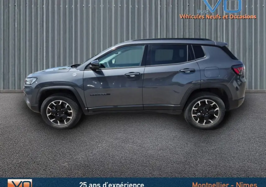 Profil côté gauche du Jeep Compass gris foncé Trailhawk 2022, SUV hybride avec jantes noires et détails robustes.