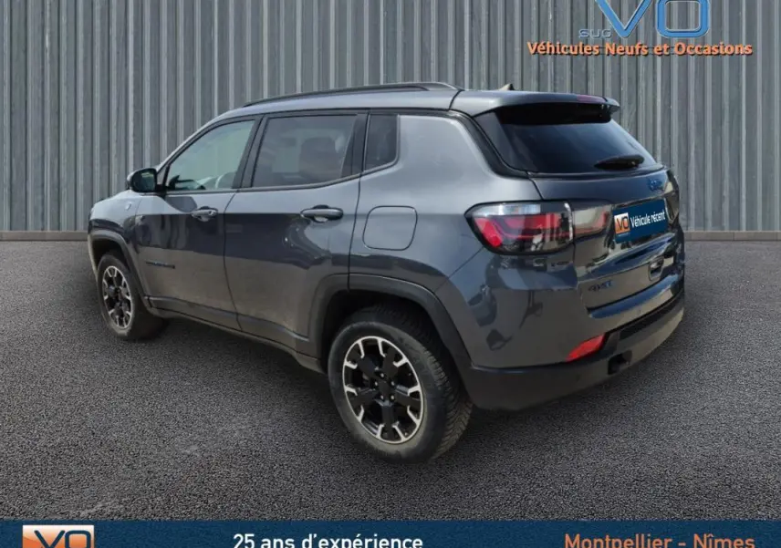 Jeep Compass gris foncé vu en 3/4 arrière droit, version hybride 4xe Trailhawk avec jantes noires distinctives.