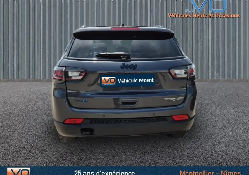 Vue arrière d'un Jeep Compass gris foncé 2022 Trailhawk avec badges 4xe et eAWD sur un sol goudronné.