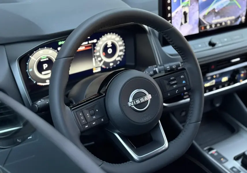 Vue rapprochée du volant cuir noir du Nissan Qashqai 2025 avec tableau de bord numérique et écran tactile.