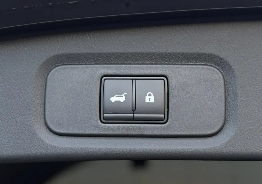 Gros plan sur les boutons d'ouverture électrique du hayon et de verrouillage dans un Nissan Qashqai gris Ceramic.