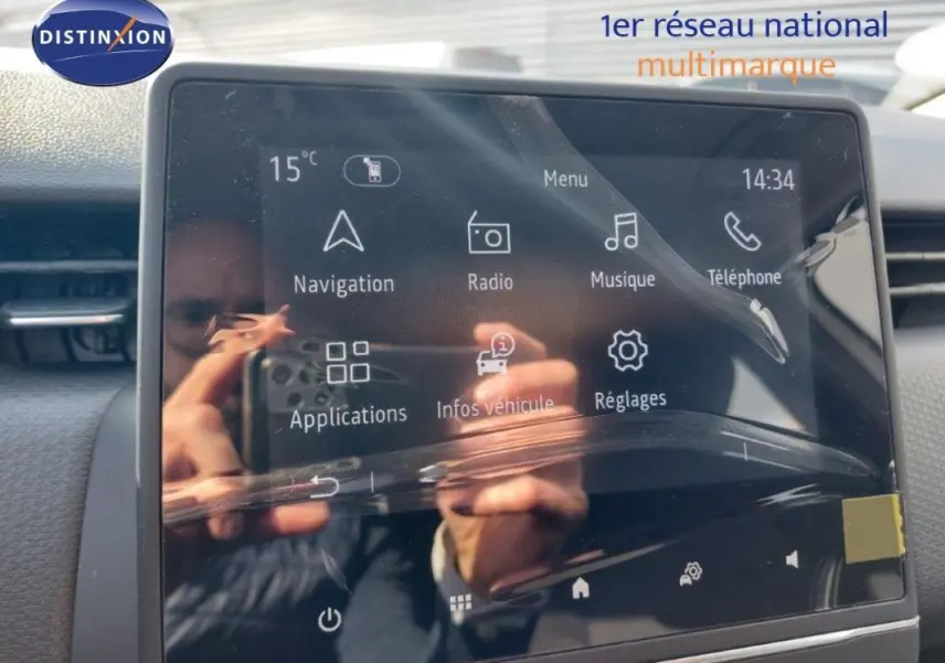 Écran tactile central de la Renault Clio V blanche, affichant le menu principal avec navigation et radio.