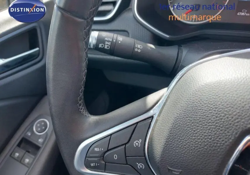 Gros plan sur le volant côté gauche de la Renault Clio blanche 2021, avec commandes du régulateur de vitesse visibles.