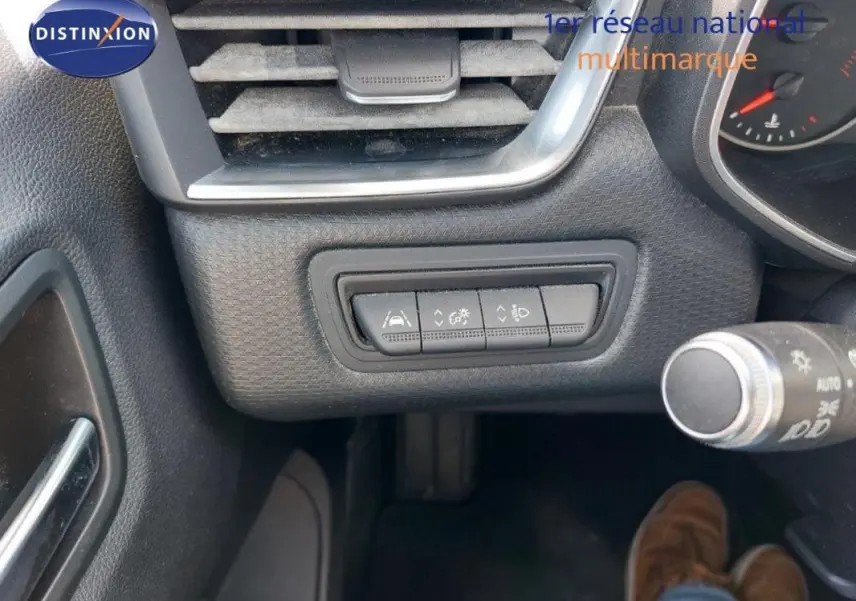 Détail du tableau de bord côté gauche de la Renault Clio blanche, montrant les commandes d'aide à la conduite.