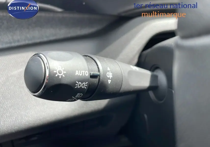 Gros plan sur la commande des phares en plastique noir dans l'habitacle d'une Peugeot 308 SW noir métal 2025.
