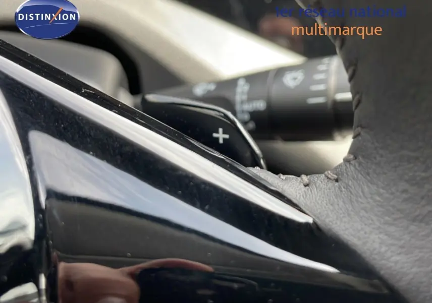 Détail du levier de vitesse automatique et du volant en cuir noir à surpiqûres dans une Peugeot 308 SW Hybrid 2025.
