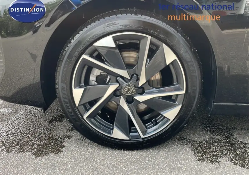 Gros plan sur la roue avant gauche noire métal d'une Peugeot 308 SW Hybrid 2025 avec jante alliage bicolore.