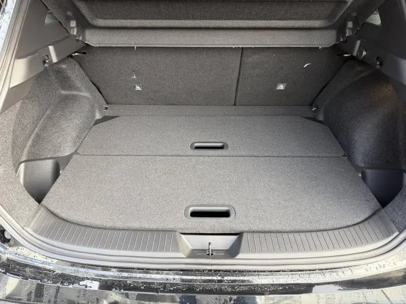 Coffre ouvert vu de l'arrière d'un Nissan Qashqai Hybrid e-POWER 2025 noir, avec plancher de chargement plat et compartiments dissimulés.