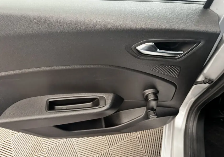 Vue intérieure côté gauche de la porte avant d'une Renault Clio Business E-TECH 140 gris clair avec poignée et manivelle de vitre.