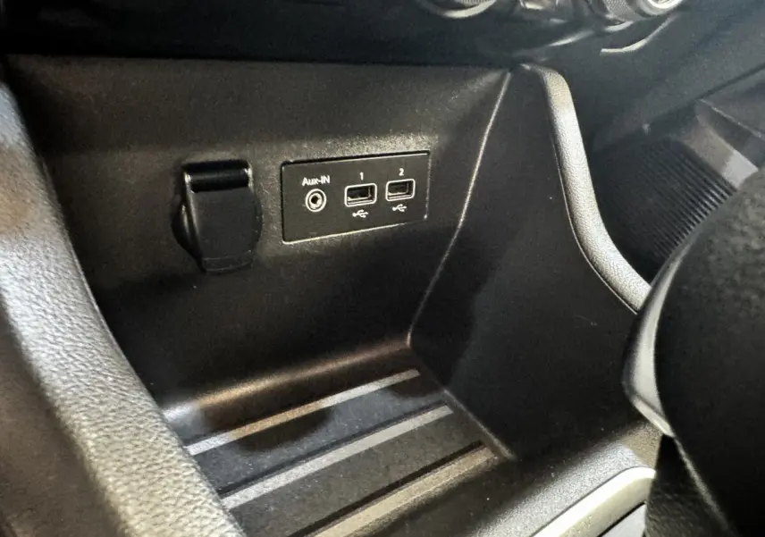 Vue rapprochée de la console centrale noire de la Renault Clio Business E-TECH 140, montrant les ports USB et prise auxiliaire.