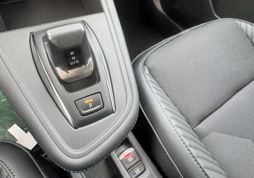 Gros plan intérieur sur la console centrale et siège gris du Renault Symbioz 1.8 E-Tech hybride, avec levier de vitesses automatique.