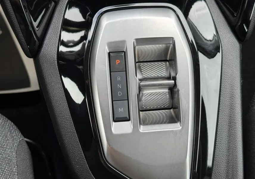Gros plan sur la console centrale noire et argentée de la Peugeot 208 1.2 Hybrid 110ch avec sélecteur de boîte auto.