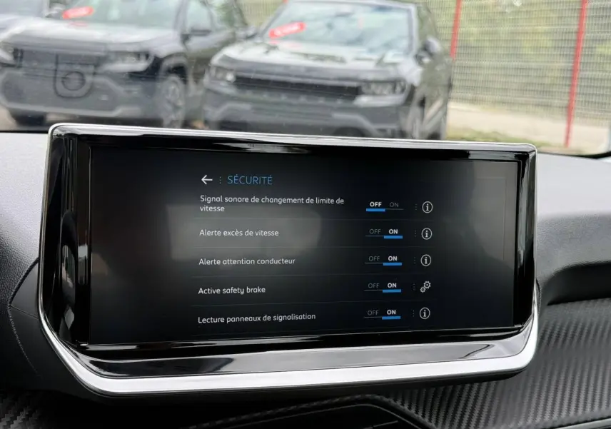 Écran tactile du tableau de bord de la Peugeot 208 noir Perla Nera, vue intérieure frontale.