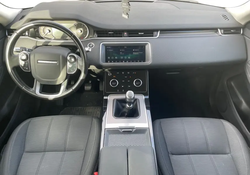 Intérieur du Range Rover Evoque 2020 blanc, vue de face sur le tableau de bord et levier de vitesses manuel.