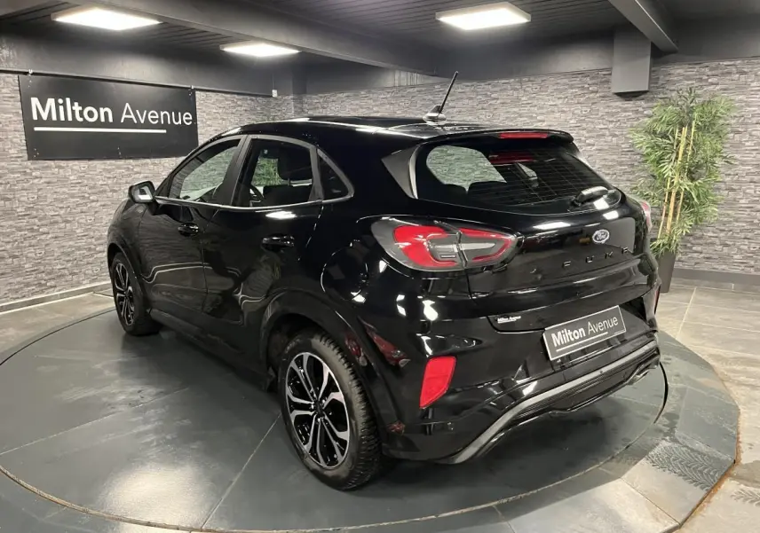 Vue 3/4 arrière droite du Ford Puma noir métallisé avec jantes alliage 17'' et badges ST-Line dans un showroom.