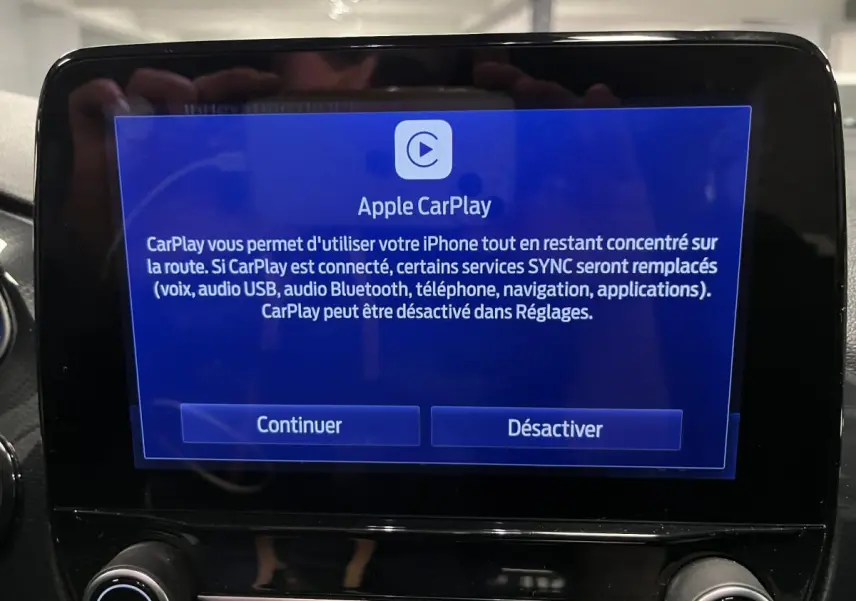 Écran tactile central affichant l'interface Apple CarPlay dans un Ford Puma noir, intérieur moderne et épuré.