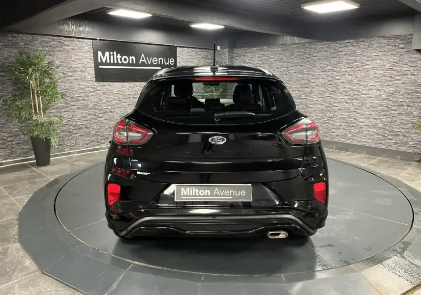 Vue arrière du Ford Puma noir brillant avec sortie d'échappement chromée et feux arrière LED en intérieur showroom