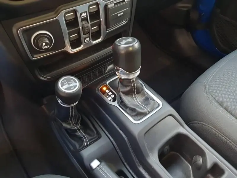 Gros plan sur la console centrale noire du Jeep Wrangler Hydro Blue 2021, montrant les leviers de vitesses automatiques et manuels.