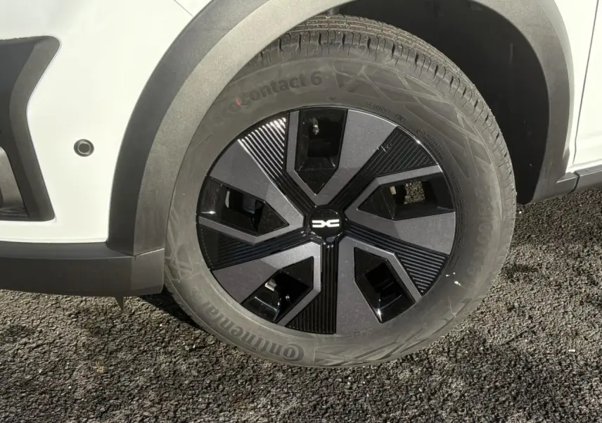 Gros plan sur la roue avant gauche noire et grise du Dacia Sandero Stepway Blanc Glacier 2024 avec capteur de stationnement.