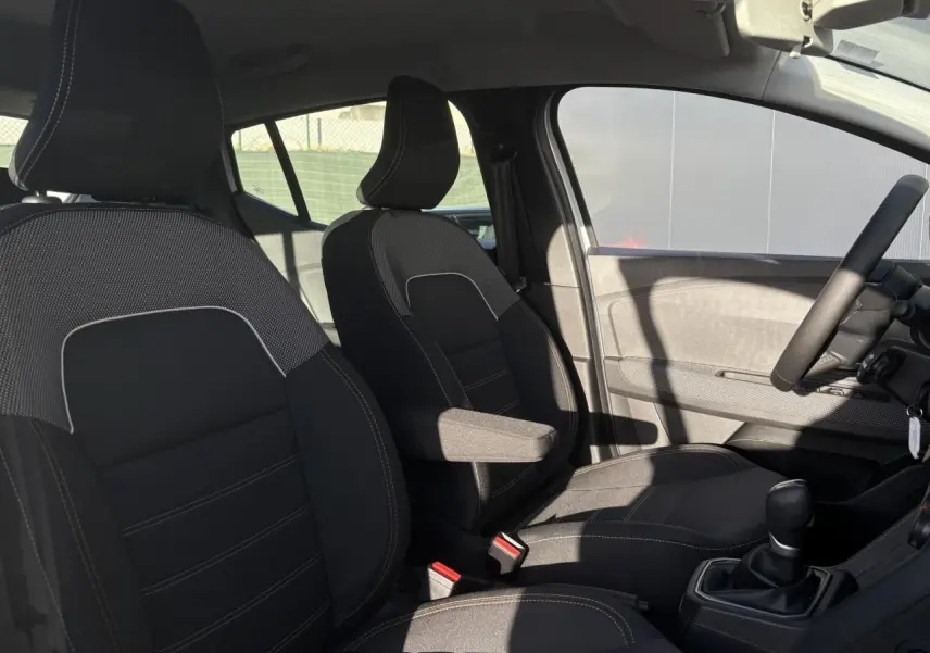 Intérieur de la DACIA Sandero Stepway 2024, vue côté droit sur sièges noirs avec accoudoir conducteur et volant.