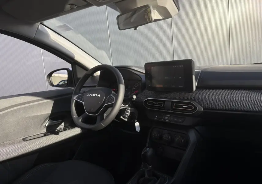 Intérieur côté conducteur de la Dacia Sandero Stepway blanc glacier, volant avec logo et écran tactile central visible