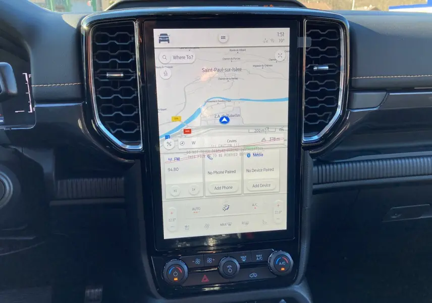 Vue rapprochée du tableau de bord noir du Ford Ranger 2025 avec écran tactile GPS vertical et commandes climatisation.