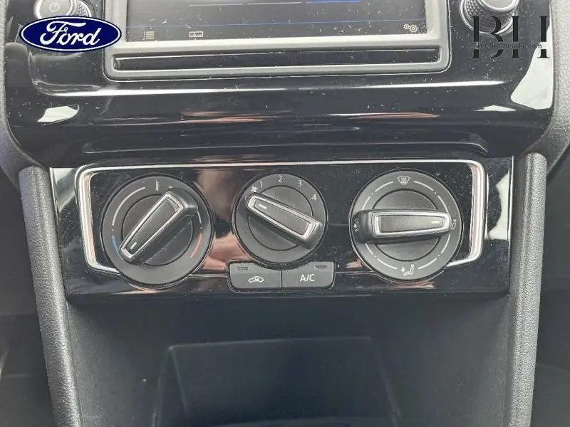 Vue rapprochée des commandes de climatisation noires sur tableau de bord d’une Volkswagen Polo noire.