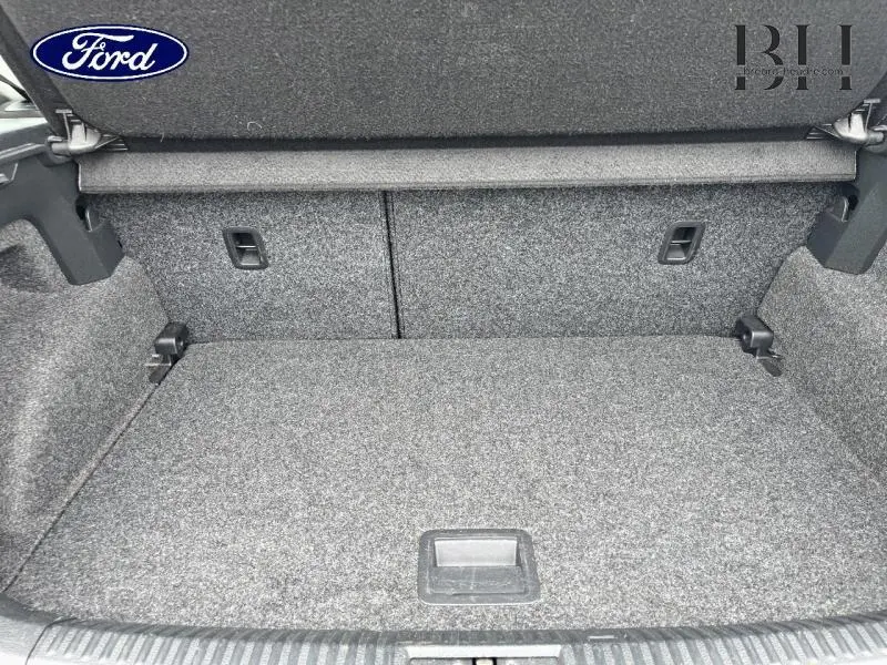 Coffre arrière vide en tissu gris d'une Volkswagen Polo 1.4 TDI noire, vue de l'intérieur vers l'arrière du véhicule.