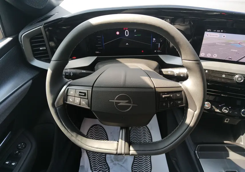 Vue intérieure centrée sur le volant gris de l'Opel Mokka Electric 2025 avec tableau de bord numérique et écran tactile.
