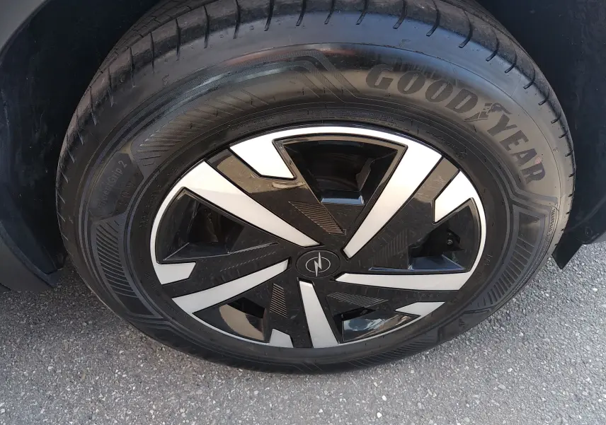 Gros plan sur la roue avant gauche d’un Opel Mokka Electric gris, avec jante noire et argentée au design géométrique.