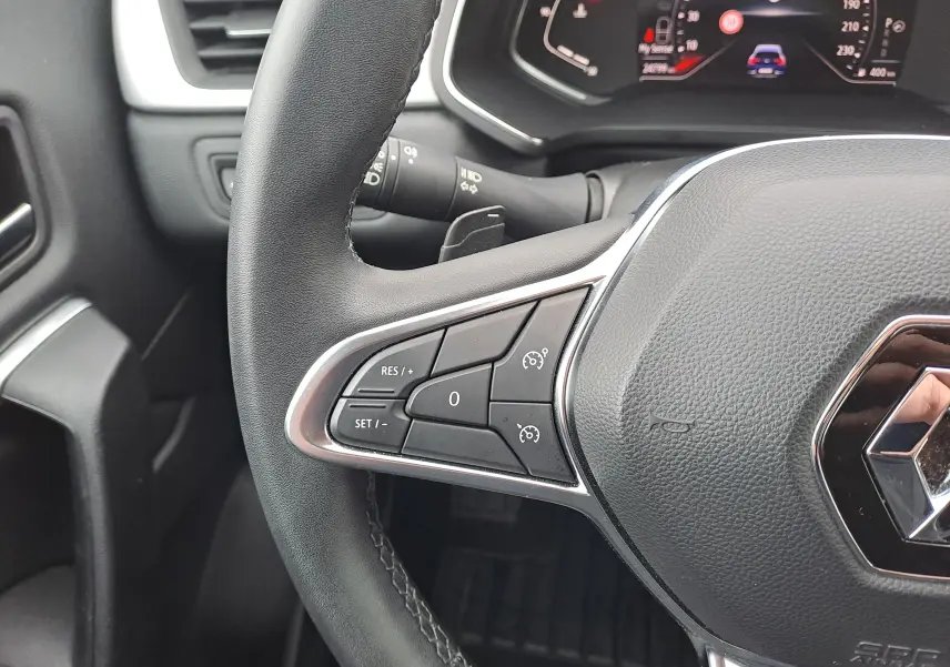 Gros plan sur le volant côté gauche du Renault Captur bleu marine 2022, avec commandes de régulateur de vitesse visibles.