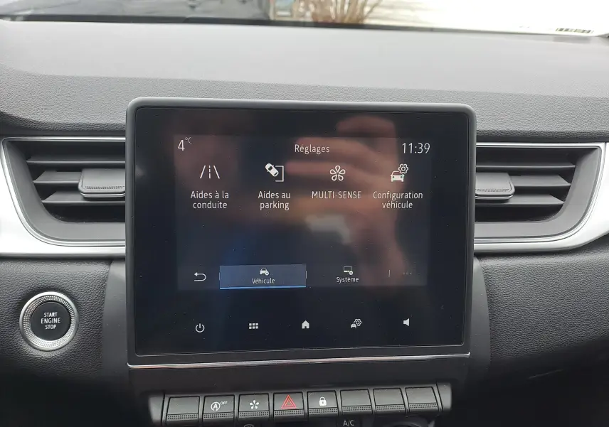 Vue rapprochée de l’écran tactile central du tableau de bord du Renault Captur bleu marine, affichant les réglages du véhicule.