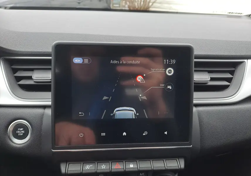 Écran tactile central du Renault Captur bleu marine 2022 montrant l'aide à la conduite et les alertes de signalisation.