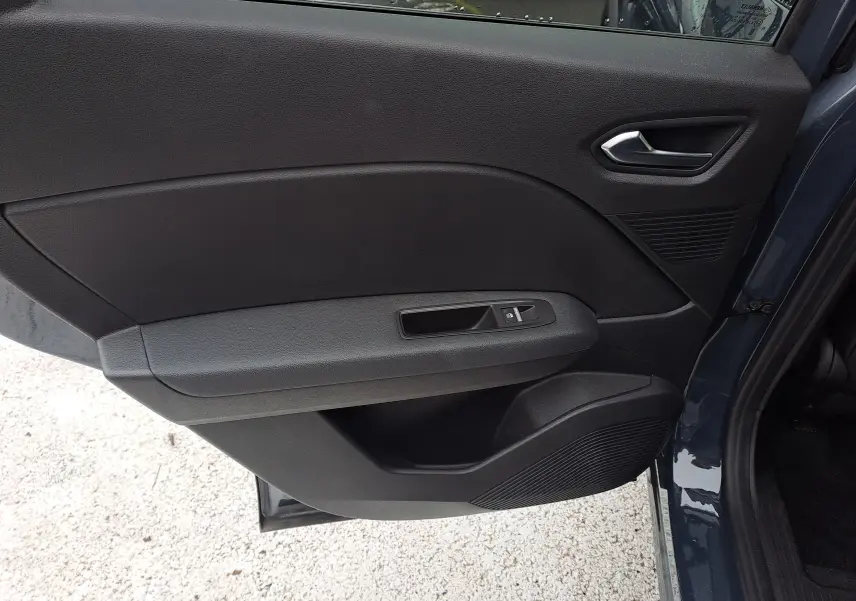 Vue intérieure côté gauche de la porte arrière d'un Renault Captur bleu marine, avec commande de vitre et poignée noire.