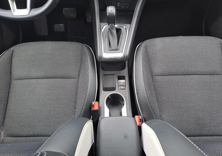 Vue intérieure centrée sur la console centrale et les sièges avant noirs avec surpiqûres blanches du Renault Captur 2022.