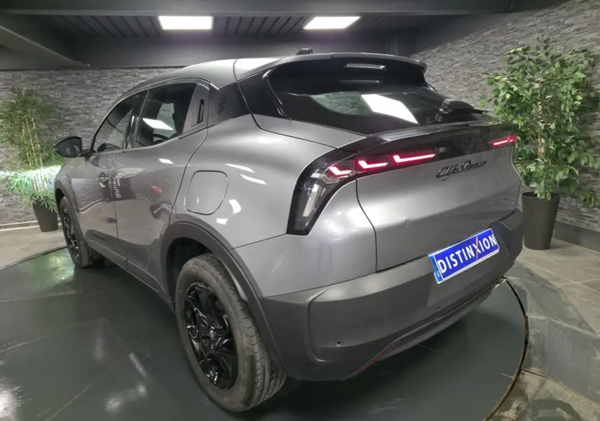 Vue 3/4 arrière gauche d'une Alfa Romeo Junior gris métallisé avec feux arrière LED et jantes noires brillantes.