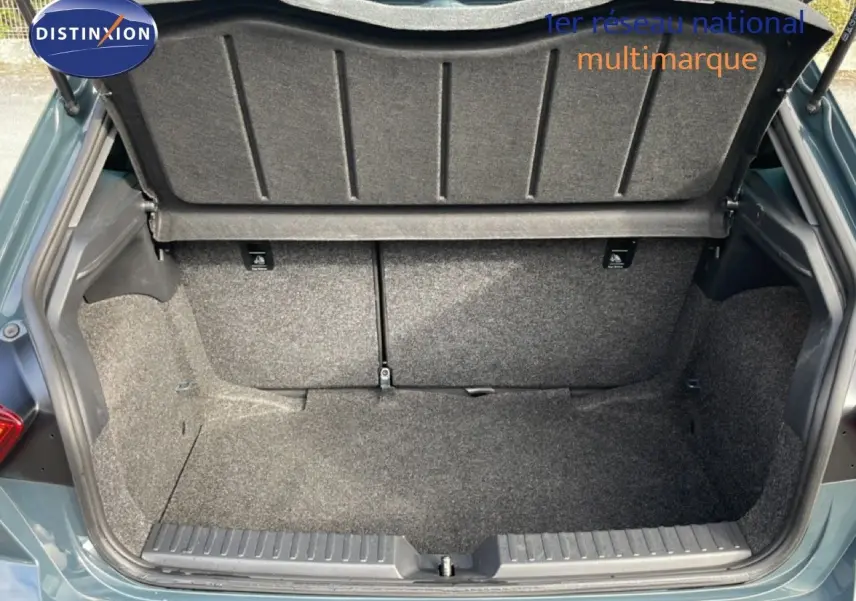 Coffre ouvert vu de l'arrière d'une SEAT Ibiza bleu Fjord, montrant l'espace de chargement vide et la moquette grise.