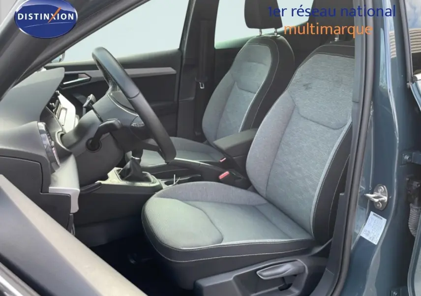 Vue intérieure côté conducteur de la SEAT IBIZA bleu fjord 2025, montrant sièges tissu gris et volant multifonction.