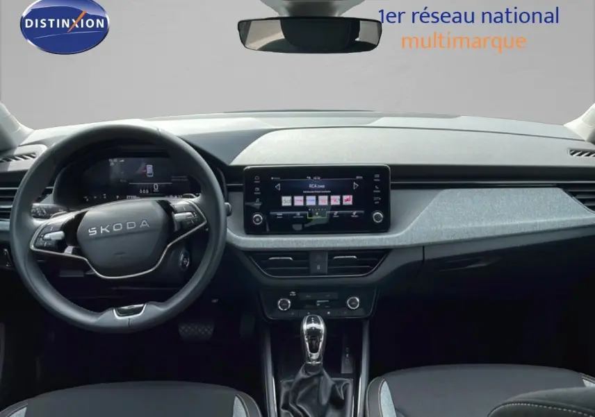 Vue intérieure frontale du tableau de bord et volant Skoda Scala 2025, finition tissu gris noir avec écran tactile central.
