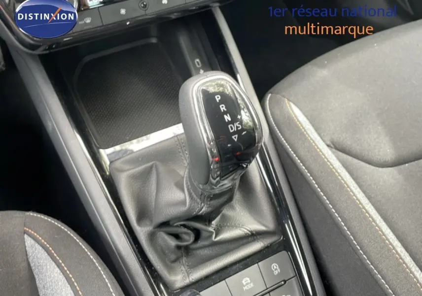 Gros plan sur la console centrale de la Skoda Scala 2025, avec levier de boîte automatique en cuir noir et siège tissu gris.