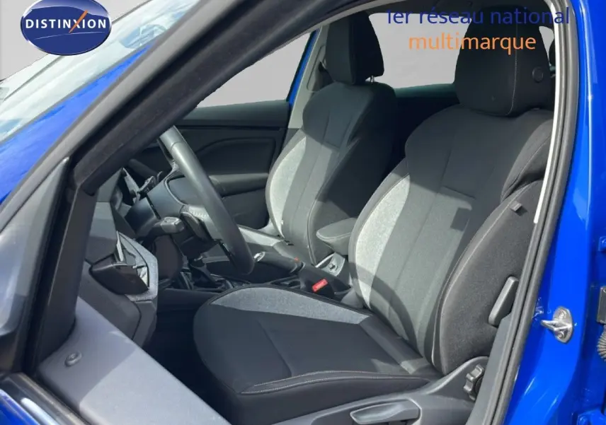 Vue intérieure côté conducteur d'une Skoda Scala 2025 bleu racing metal, sièges tissu gris et noir avec volant multifonction.