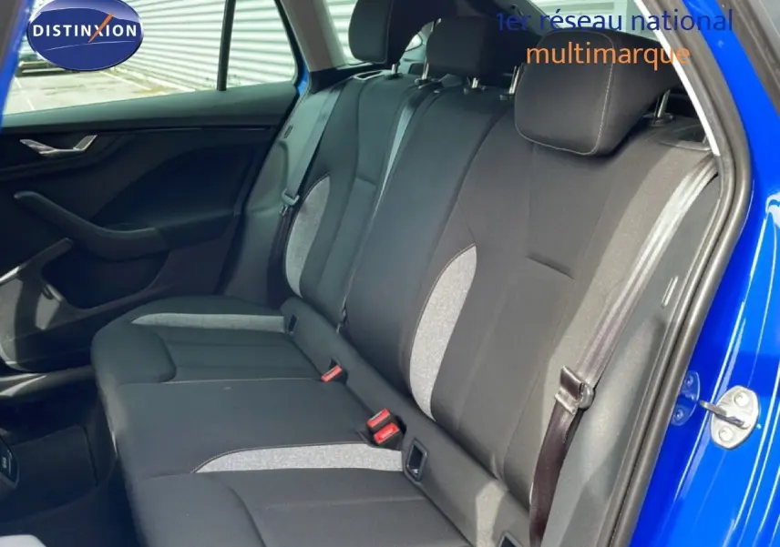 Vue côté droit de l’intérieur arrière d’une Skoda Scala bleu racing metal avec sièges tissu noir et gris clair.