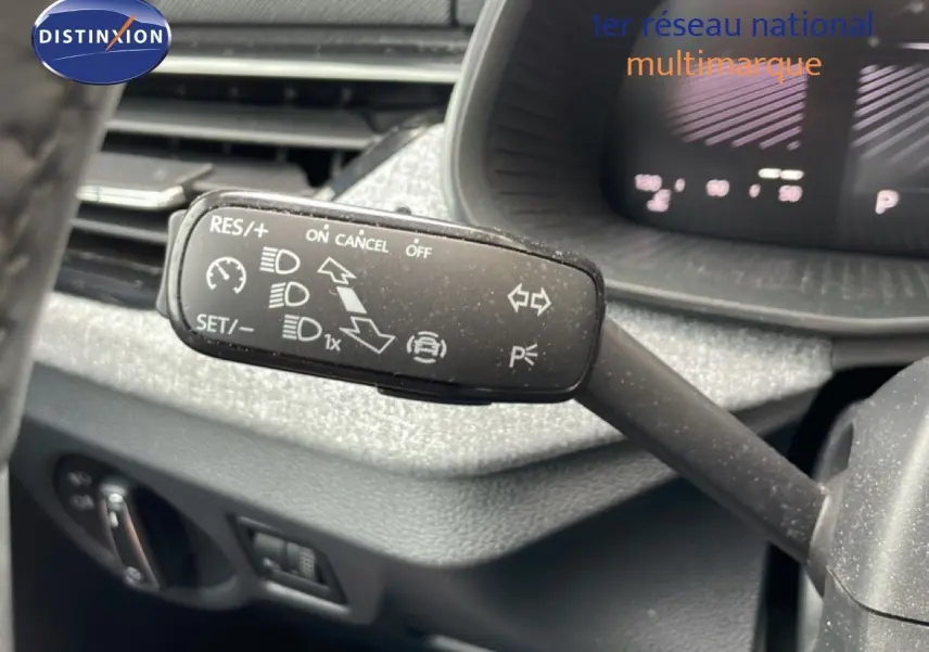 Gros plan sur la commande de régulateur de vitesse à gauche du volant dans l’habitacle gris foncé d’une Skoda Scala 2025.